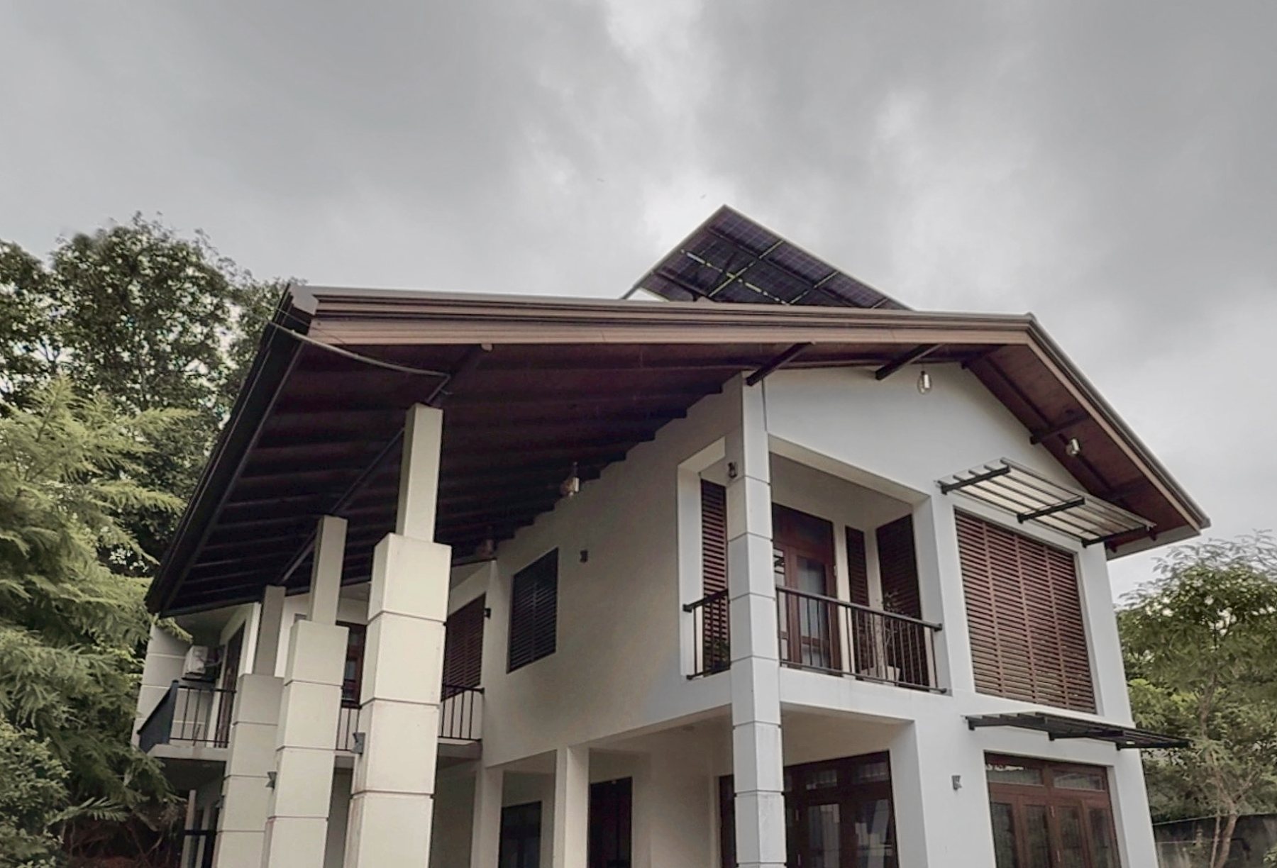 Completed family residence with white walls, timber louvres, deep roof eaves and rooftop solar panels